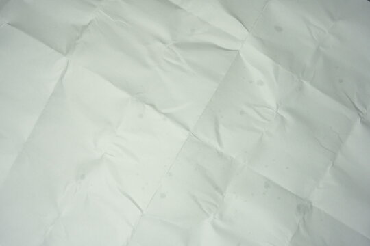 Texture of crumpled and folded white paper. Background of messy creased paper sheet with grid lines from folding, top view surface texture.