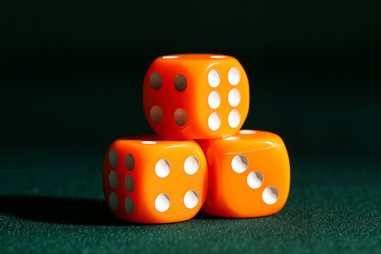 Orange game dices on green background, closeup