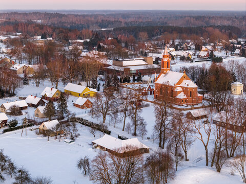 Aerial view of the red brick Church of Our Lady of the Scapular and snow-covered houses in the historic village of Kernave, Vilnius County, Lithuania.