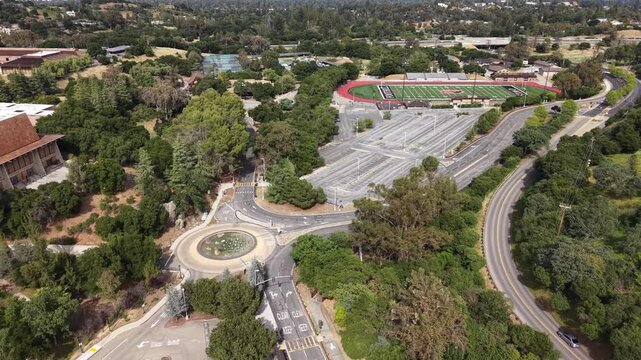 High-altitude aerial view revealing the scenic Foothill College campus nestled in Los Altos Hills, showcasing its modern architecture, lush green surroundings, and expansive parking lots