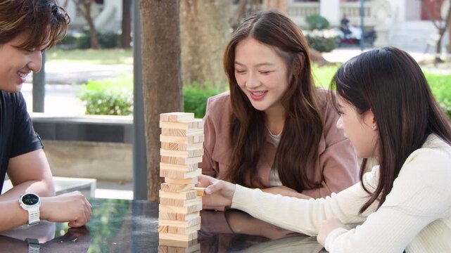 Thai University Students Playing Wooden Block Tower Game Outdoors