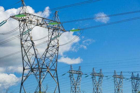 High Voltage Electricity Pylons With Green Insulators Against Blue Sky