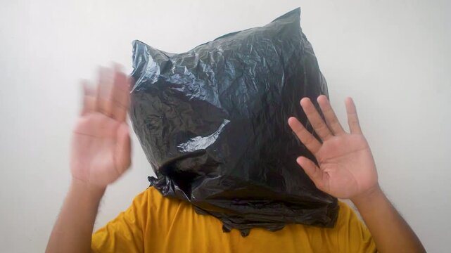 Man with plastic bag over head surrendering with hands up, concept of desperation, crime, or protest