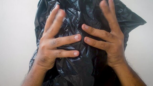 Man hides his face with a trash bag in fear or despair, representing anxiety and social isolation