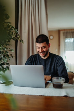 Man smiling working from home using laptop