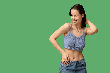 Obraz premium Beautiful young happy woman with piercing navel on green background