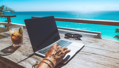 Obraz premium Embrace the digital nomad lifestyle with this scene of remote work on a tropical balcony. Featuring a laptop, refreshing drink, and ocean views, it represents freedom and modern business.