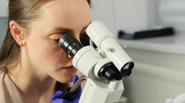 Gynecologist performs microscopic inspection during cervical screening session. Specialist observes sample closely verifying diagnostic details