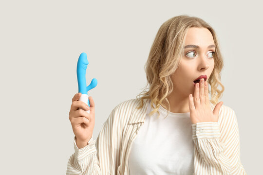 Shocked young woman with vibrator on white background