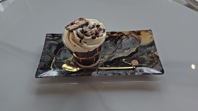 chocolate portioned dessert in a glass cup with a gold spoon on a rectangular plate Sweets on stands. Delicious desserts at the banquet, sponge cakes, shortbread tarts. move camera footage. Close up