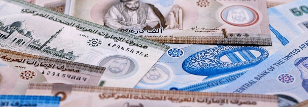 UAE dirham money bills pile on table. United Arab Emirates banknotes of AED currency close up.