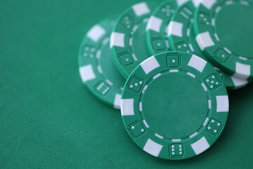Naklejka premium Green casino poker chips on green gaming table close up. Few amount of green casino chips.
