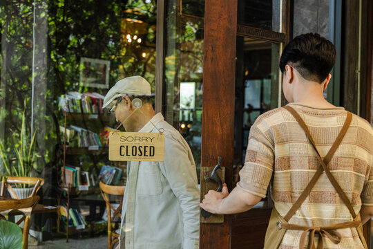Small business cafe owner guiding young barista, father and son discussing table setup while holding tablet, small business workflow planning and service improvement in cozy restaurant and coffee shop