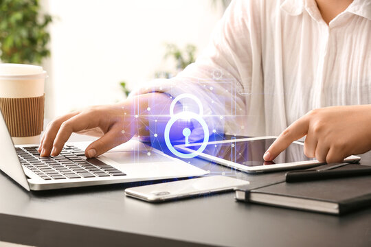 Female programmer working with laptop and tablet computer at her workplace in office, closeup