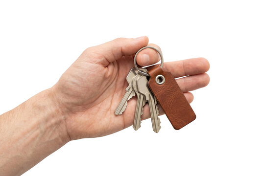 Hand holding keys with leather keychain front view isolated. Real estate agent mockup.
