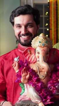 Indian family dressed in traditional attire, joyfully welcomes Ganapati Bappa with a lighted samai and pooja thali, embracing the festive spirit of Ganesh Chaturthi with love and devotion