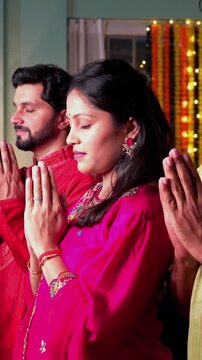 An Indian family dressed traditionally, lights samai and prays with folded hands seeking divine blessings for love and togetherness