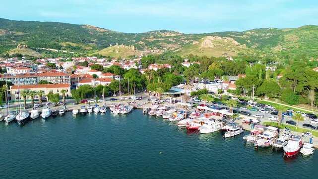 Aerial view of a bustling harbor filled with boats and a scenic coastal town. Turkey, Izmir, Eski Foca