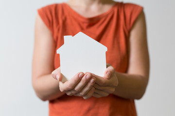 Obraz premium Person's hands cradle a small white house shape representing home ownership