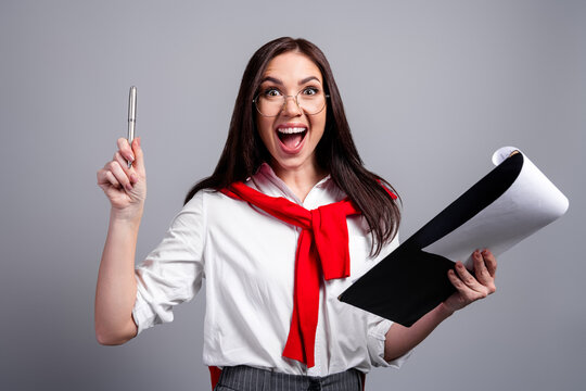 Excited business woman holding documents and pen celebrating new idea during presentation or meeting with joyful expression