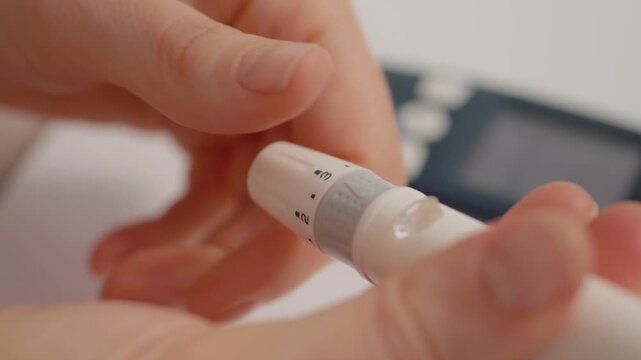 A woman holds a finger pricking device in her hands to test blood sugar levels. This process is important for managing diabetes and checking glucose levels.