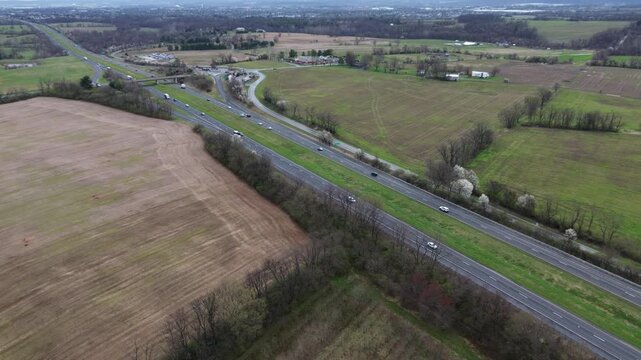Rural interchange span at US15 junction near Elmer Derr Rd with multilane traffic, looping ramps, surrounding farmland shaping western Frederick corridor muted field textures, trees, Maryland