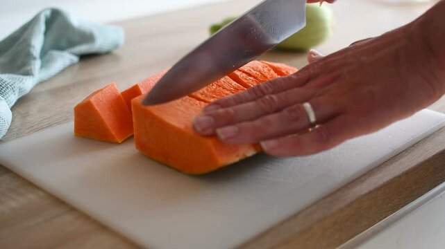 Cutting fresh pumpkin on wooden cutting board. Close up