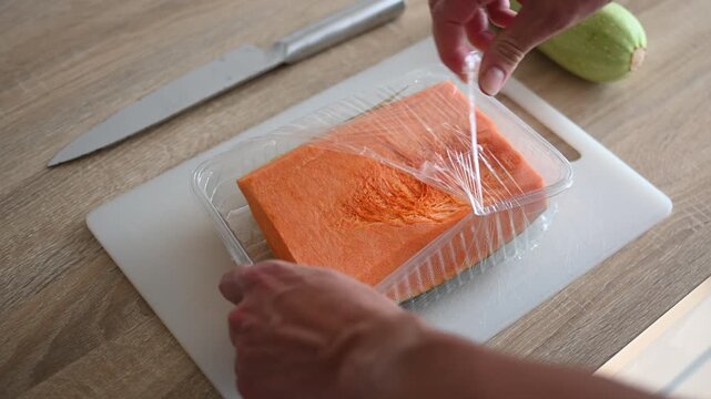Unpacking fresh pumpkin from plastic tray in kitchen close up