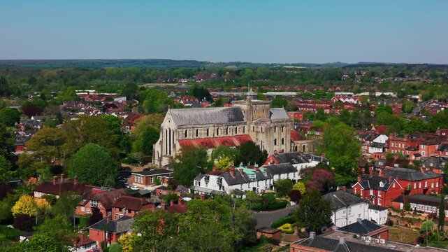Drone aerial view of Romsey Abbey surrounded by rooftops, trees and the historic town centre of Romsey in Hampshire, England.