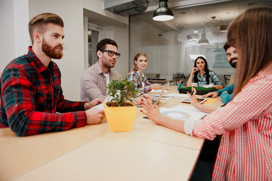 Young creative team in a business meeting around a table in a modern office collaborating on a project