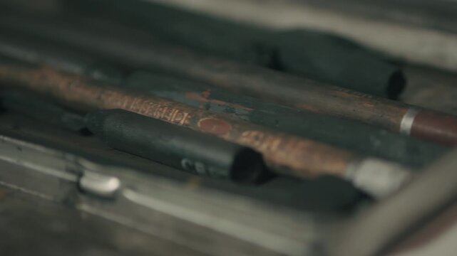 Macro slide across charcoal sticks resting on a finished drawing, evoking completion, pause, and the quiet aftermath of a creative session.