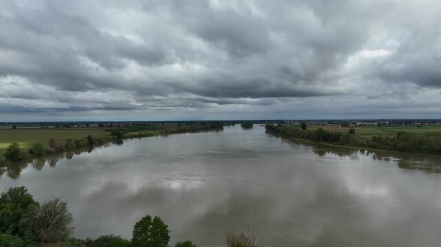 Drone shows confluence of Trebbia River and Po River near Piacenza Emilia Romagna with sediment mixing, wide channel morphology and floodplain farmland, aerial shot