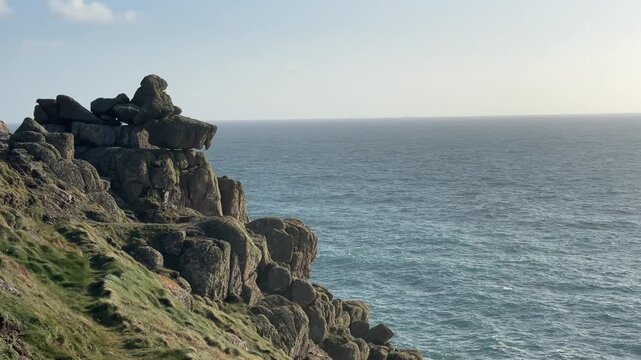 Rugged granite cliffs at Lands End in Cornwall overlooking vast Atlantic Ocean on clear day with textured rock formations and coastal landscape creating dramatic natural scene