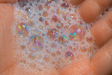 Fototapeta premium Macro closeup of colorful soap bubbles in human hands with iridescent reflections