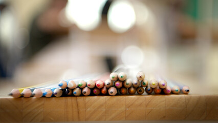 Naklejka premium Colored pencils arranged on a wooden table with soft blurred classroom background