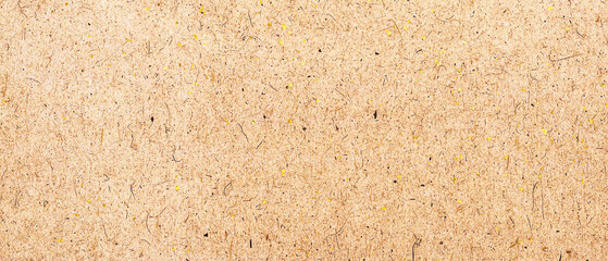Fototapeta premium Close up of a light brown textured paper background with small dark fibers and yellow flecks, rustic craft paper surface