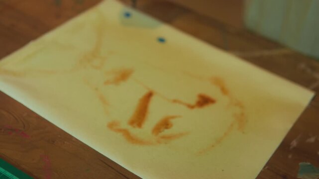 Close up artist dropping ink on portrait drawing with slight camera move