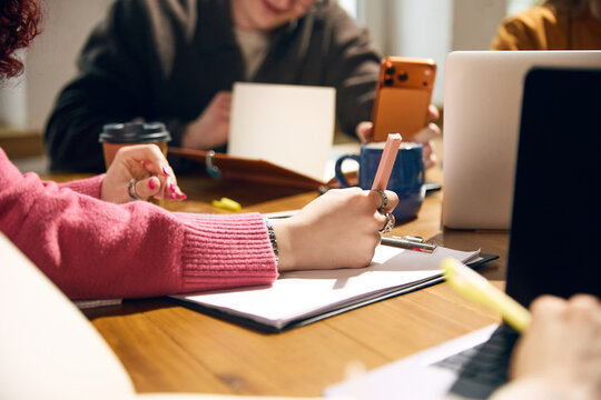 Hands taking notes during collaborative study and business planning session. Concept of education, project workflow, startup meeting, creative research, training materials, and office teamwork.