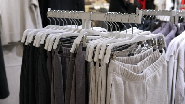 Professional retail shot of stylish sweatpants on a rack. Perfect for fashion documentaries, shopping vlogs, or commercials. High-quality fabric textures and minimalist aesthetic for a trendy clothing