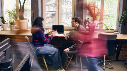 Fototapeta na wymiar Focused office workers having one on one business conversation in coworking space. Concept of mentoring, feedback session, client briefing, HR meeting, startup coaching, and team communication.