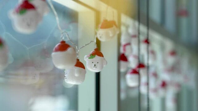 Cute hanging bear string lights with Santa hats reflected in window glass, cozy festive atmosphere with warm light, bokeh and cinematic shallow depth of field, decorativel holiday 