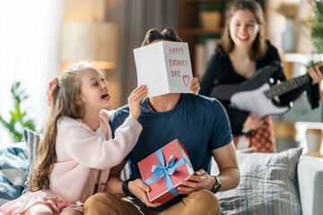 Naklejka premium Joyful Family Celebrating Father?s Day with Gifts, Card, and Music at Home