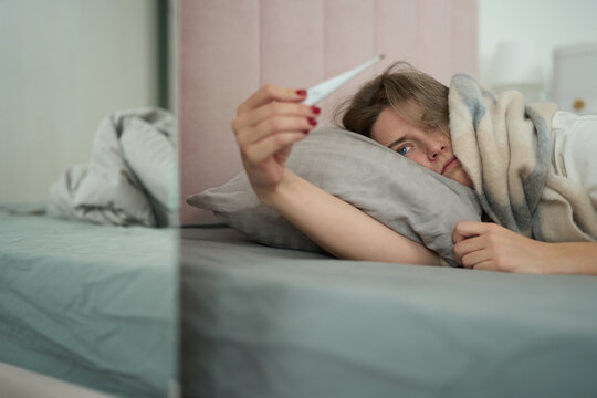 Sick and Resting While Examining Thermometer
