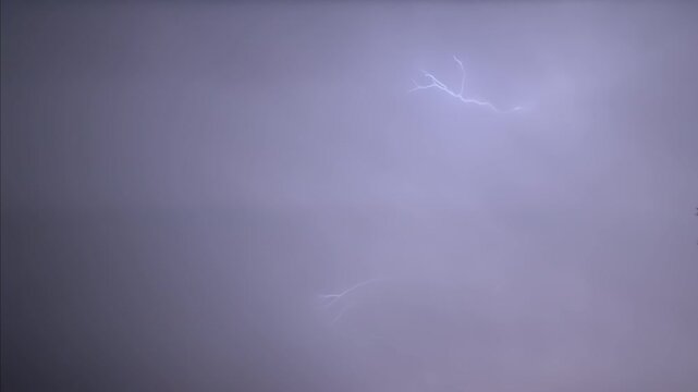 Isolated lightning bolt in the night sky, captured in slow motion.