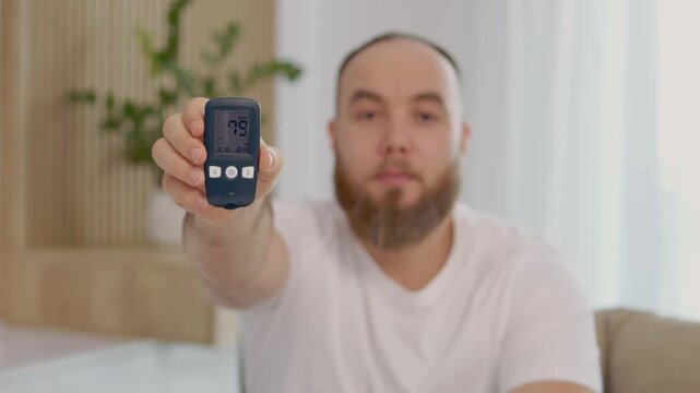 A man displays a glucometer reading of 79 mg dL, indicating a good glucose level in a bright living room. He shares insights on managing diabetes and blood sugar.