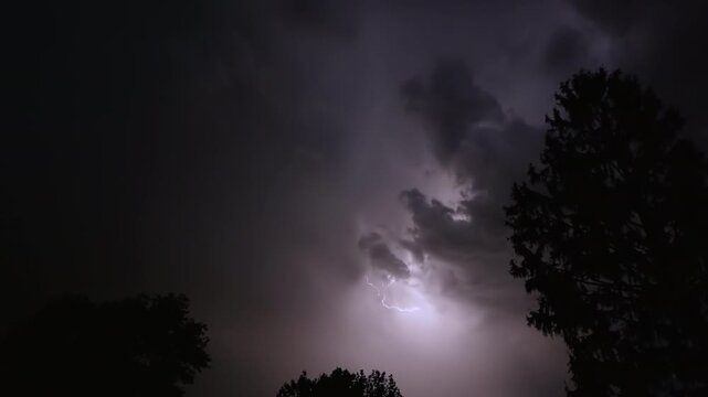 Lightning strikes on a dark night sky over a city landscape, captured in slow motion.