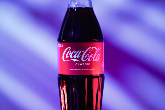 Tyumen, Russia-April 20, 2026: Plastic bottle of Coca-Cola Classic 0.33L against a blue striped background