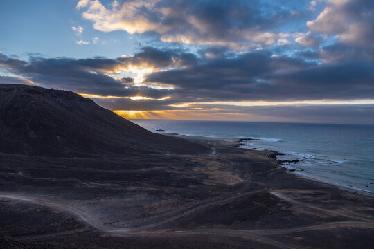 A beautiful sunrise with an impressive cloudscape over the Atlantic Ocean coastal sand dunes and desert-like terrain around Kite beach and Santa Marie on Sal Island in Cape Verde. This unique national