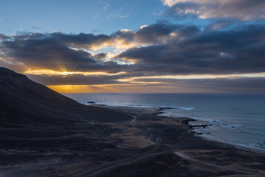 A beautiful sunrise with an impressive cloudscape over the Atlantic Ocean coastal sand dunes and desert-like terrain around Kite beach and Santa Marie on Sal Island in Cape Verde. This unique national