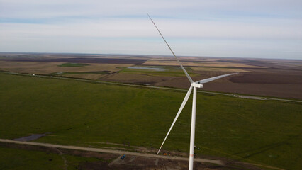 Aerial View of a Large Wind Turbine in a Green Field Under a Cloudy Sky © Andrey